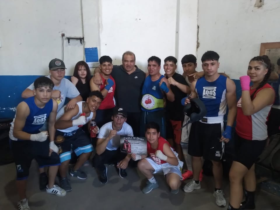Equipo de boxeo de la Asociación Quilmeña Deporte y Salud posando en el gimnasio con Pedro Franco